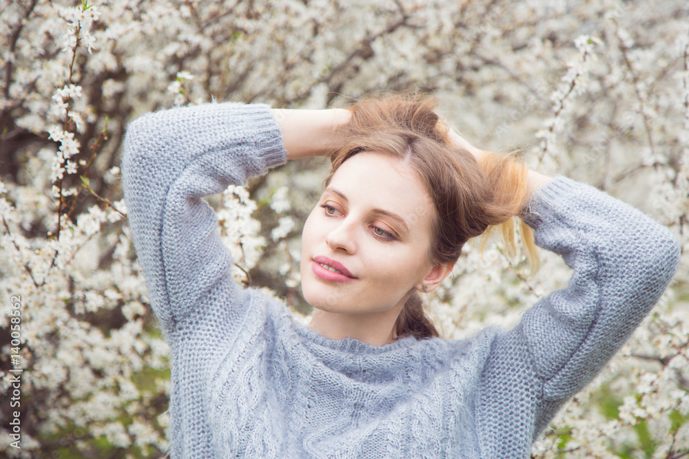 Beautiful blond young woman standing in front of wonderful blooming trees in spring garden Beautiful blond young woman standing in front of wonderful blooming trees in spring garden