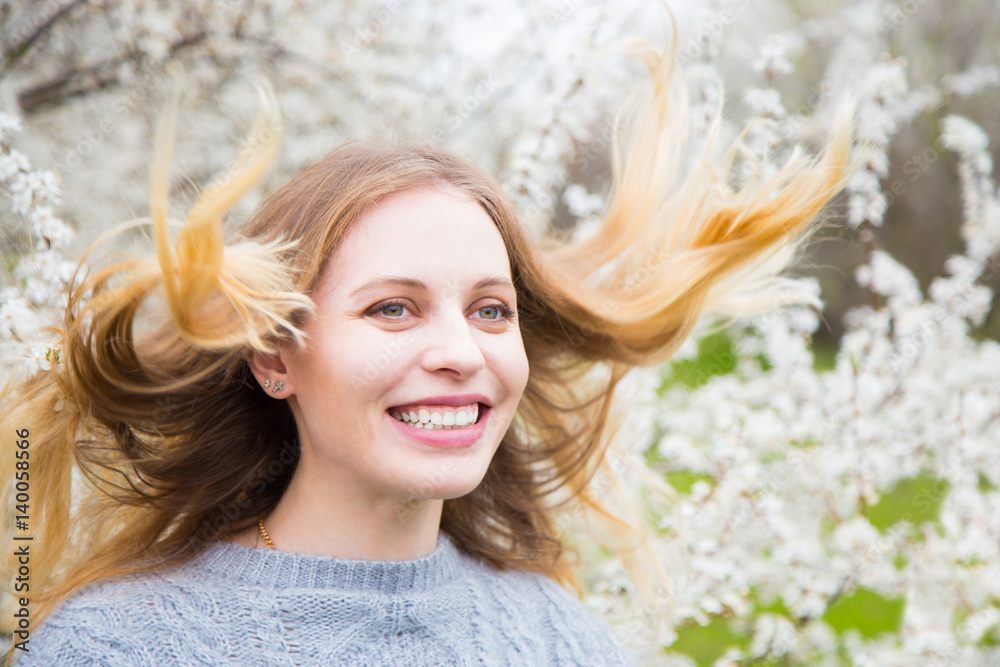 Beautiful blond young woman standing in front of wonderful blooming trees in spring garden Beautiful blond young woman standing in front of wonderful blooming trees in spring garden