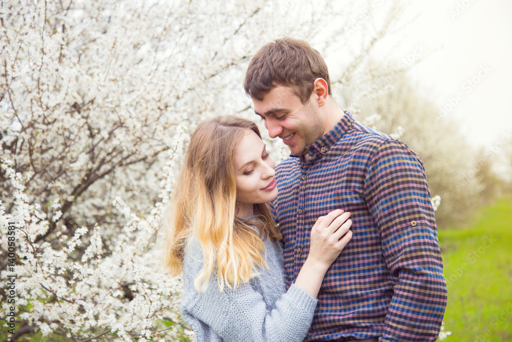 Young romantic couple standing in front of wonderful blooming trees in spring garden Young romantic couple standing in front of wonderful blooming trees in spring garden