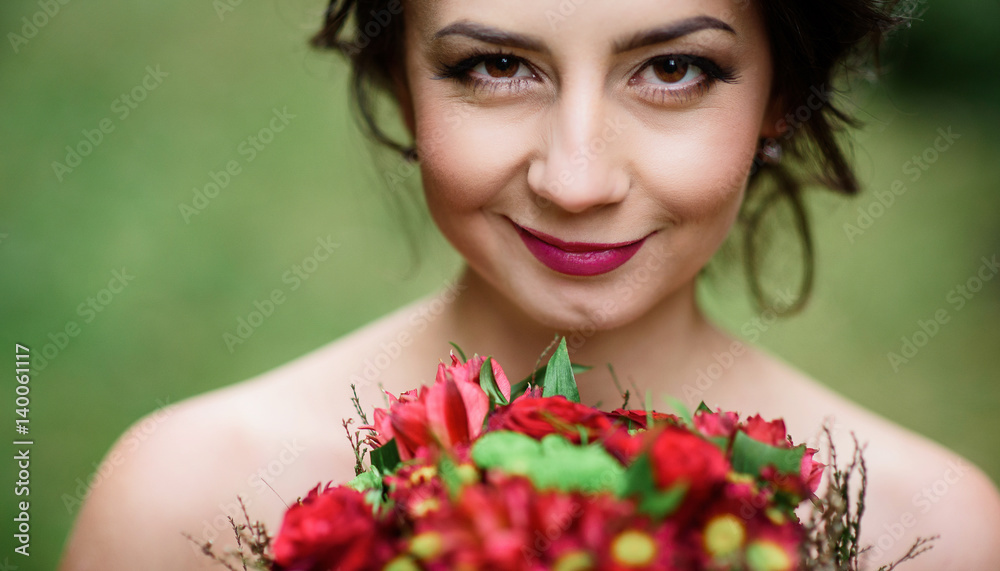 Fototapeta premium Bride with shiny dark hair holds red wedding bouquet