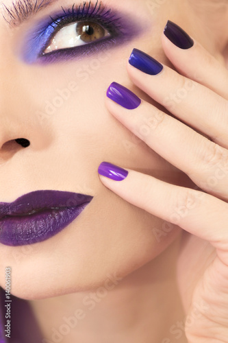 Blue purple fashion multicolored manicure and makeup on a woman in close-up.