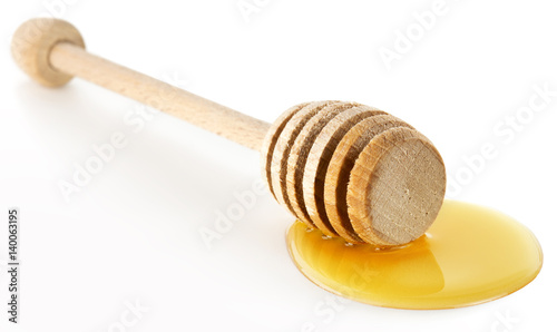wooden honey dipper over a honey drop isolated on white background