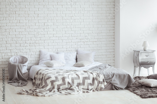Bedroom interior with a brick wall with a bed and bedside tables photo