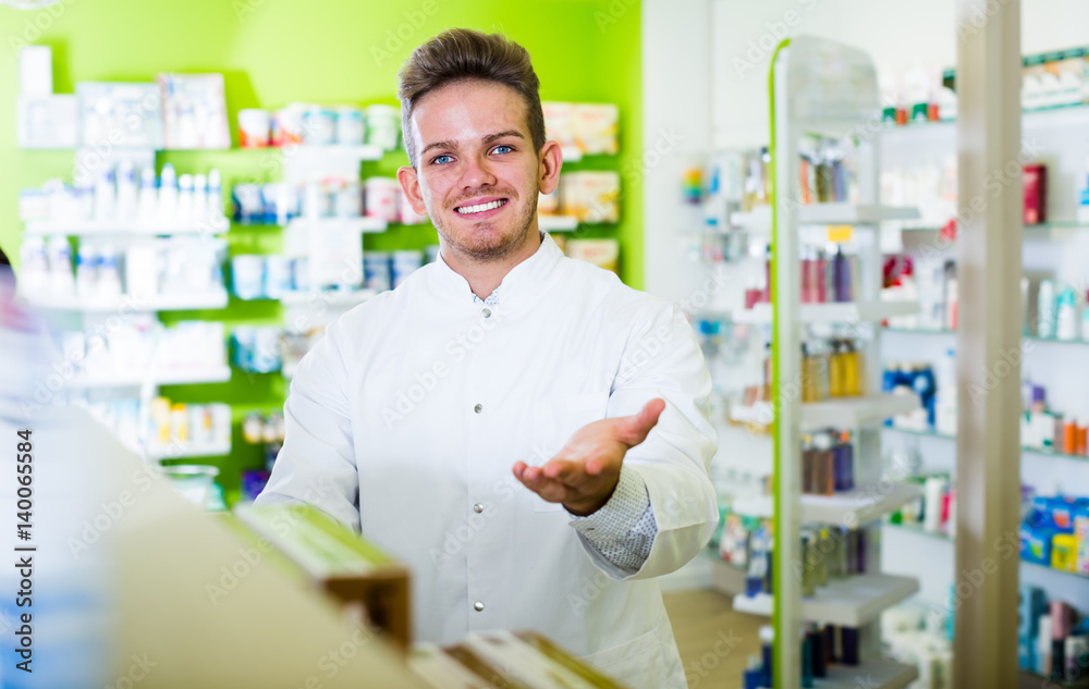 Laughing pharmacist standing among shelves