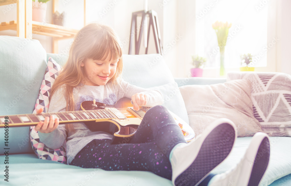Cute little girl playing guitar at home