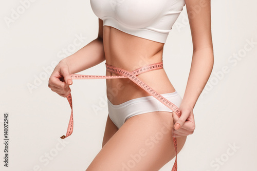 The girl taking measurements of her body, white background. photo