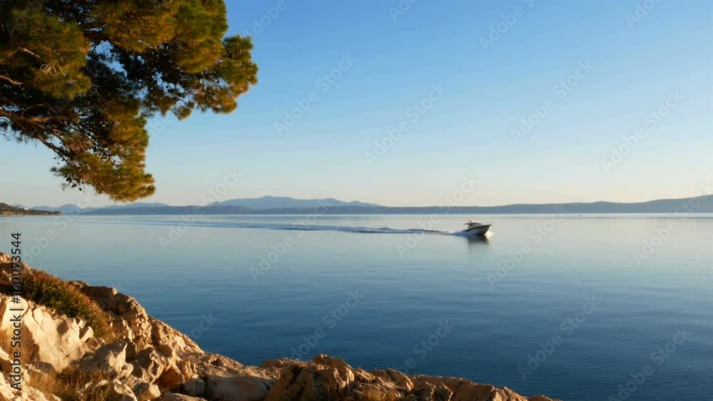 Speed boat passing by scenic coastline of Adriatic sea on sunny day Speed boat passing by scenic coastline of Adriatic sea on sunny day