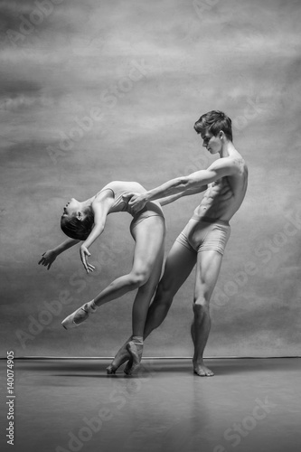 Couple of ballet dancers posing over gray background
