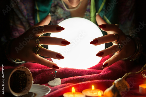 Hands of an female fortune teller around a crystal ball