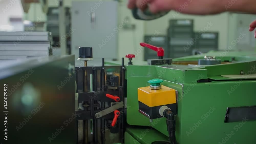A young woman who is working in the factory is putting one item to the side and the other one on a machine.
A young woman who is working in the factory is putting one item to the side and the other one on a machine.