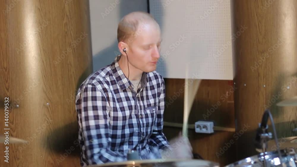 Handsome guy behind the drum kit in shirt and trousers plays the drums