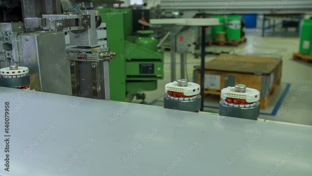 Two items are travelling on a conveyor belt in a factory and they are approaching the robotic machine.

