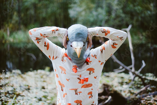 man in a rubber bird mask standing in a weird pose in the forest photo