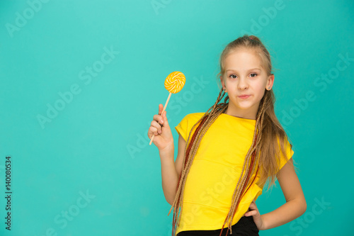 The teen girl with colorful lollipop on a blue background
