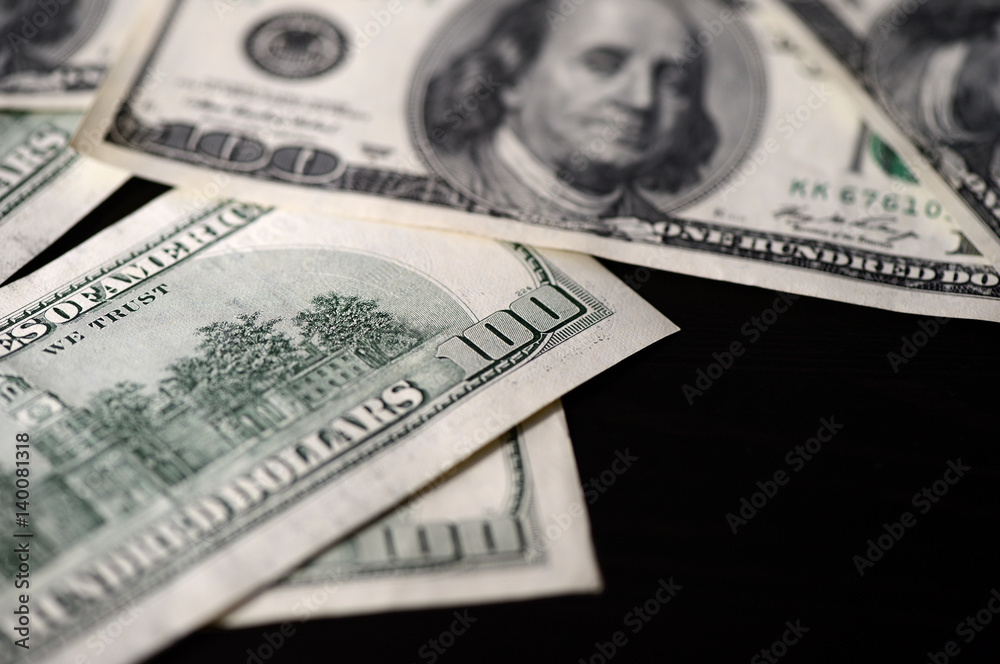 A pack of hundred dollar bills on a dark background A pack of hundred dollar bills on a dark background
