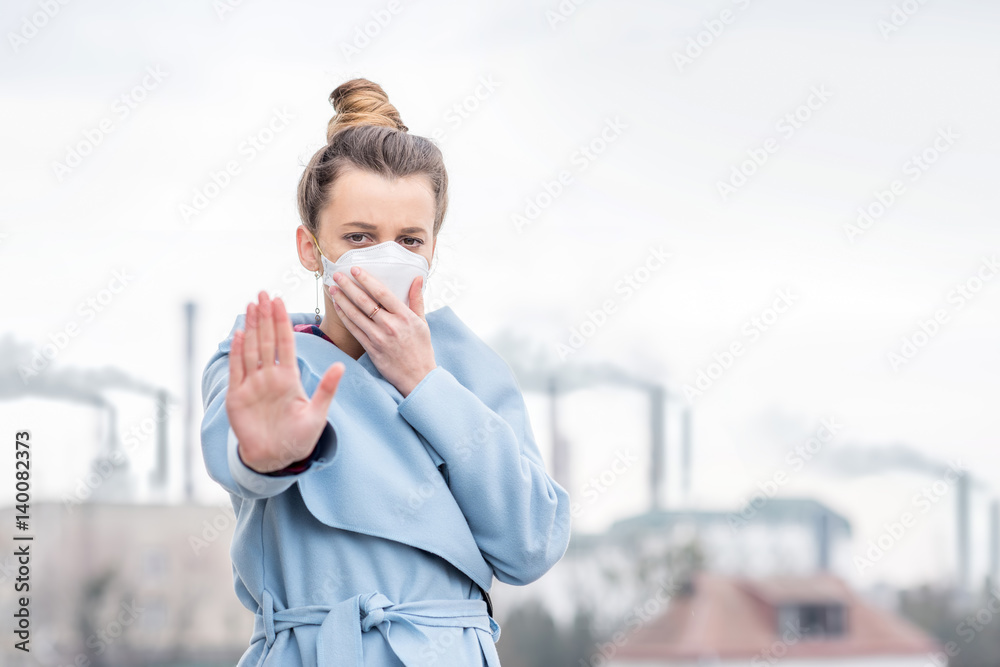 Plakat Młoda kobieta w masce ochronnej cierpiących na zanieczyszczenie powietrza z dużej produkcji w mieście