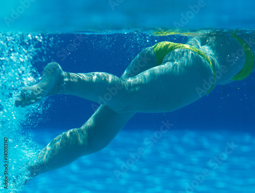Woman swimming underwater in the swimming pool.