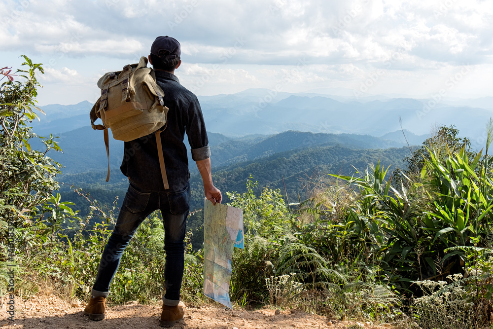 Young Man Traveler with map backpack relaxing outdoor with rocky mountains on background Summer vacations and Lifestyle hiking concept