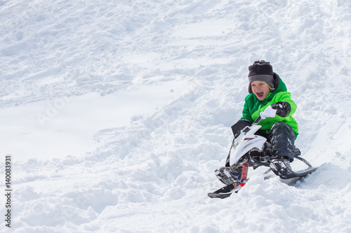 Boy riding a sled tobogganing in the snow