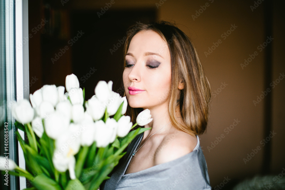 Naklejka premium A girl holds a bouquet of white tulips
