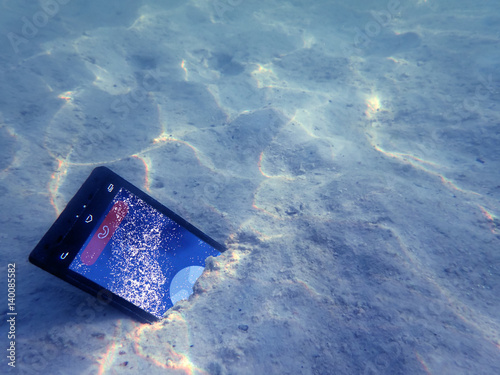Mobile phones on the sand under the sea water. 