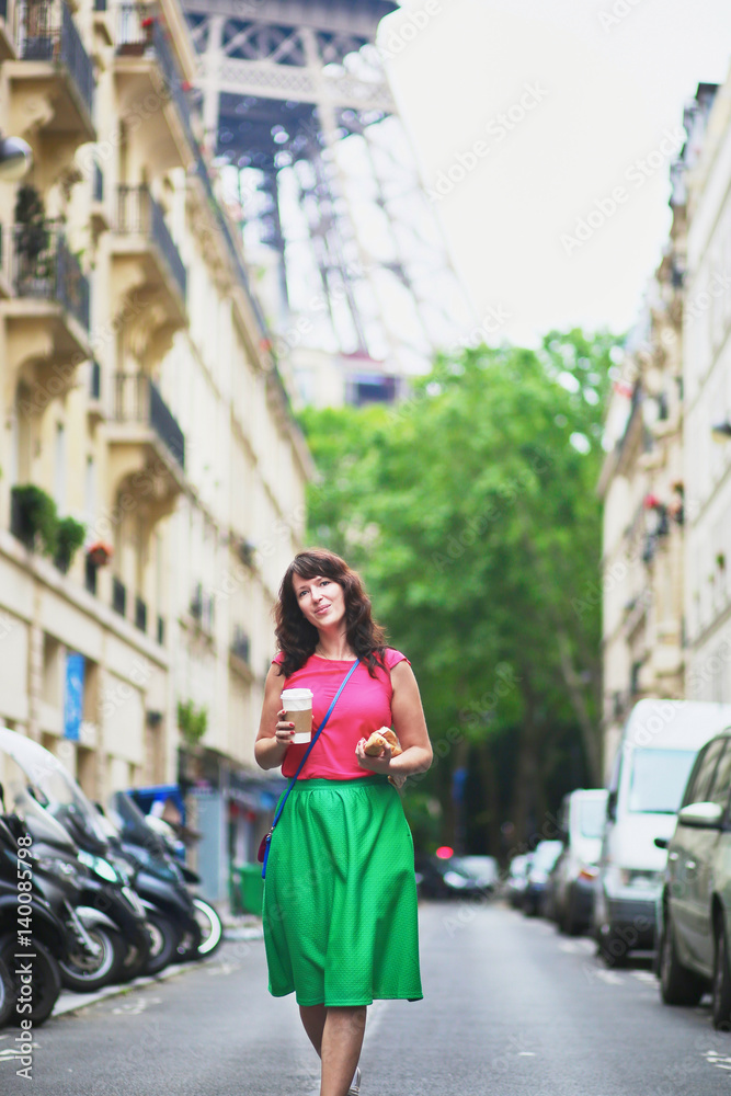French woman walking with coffee to go and baguette on a street of Paris