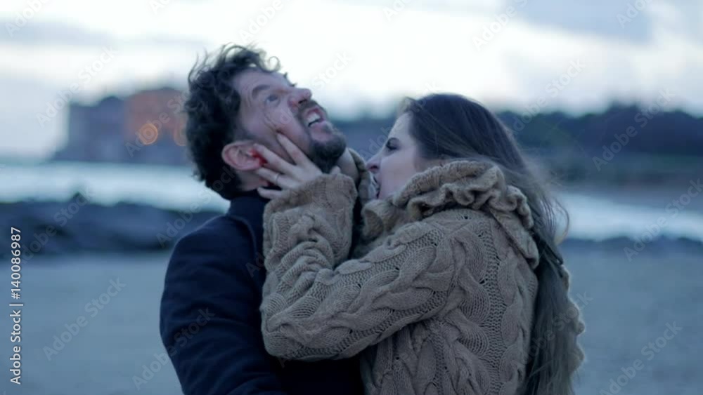Hungry beautiful female vampire trying to bite scared man on the beach slow motion