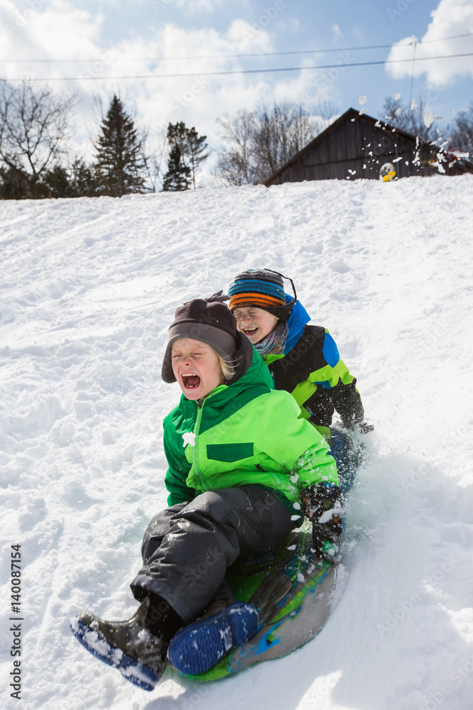 Boys riding a sled, tobogganing down the snow Boys riding a sled, tobogganing down the snow