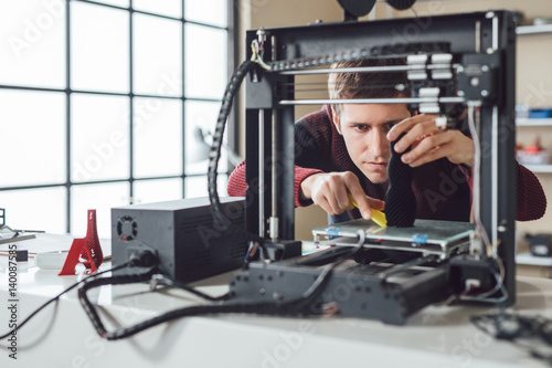 A men detaching new made object from 3d printer. photo