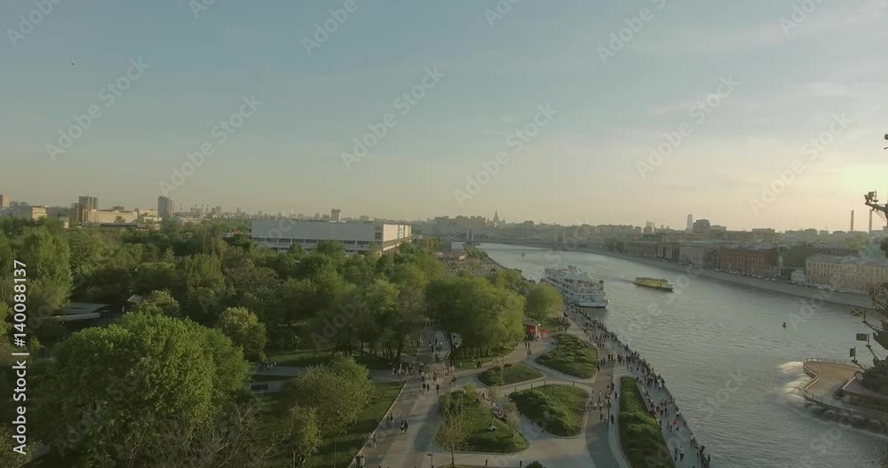 Aerial view of Peter the Great Statue on a spring day at sunset. Crowds of people walking along the park near river. Aerial view of Peter the Great Statue on a spring day at sunset. Crowds of people walking along the park near river.