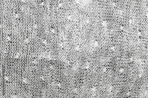 Patterned woolen cloth. White on a black background. Texture.
