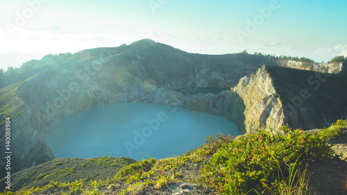 High panoramic view of the green turquoise colored lake in the Kelimutu volcano during the morning at sunrise with nobody around, Indonesia.
