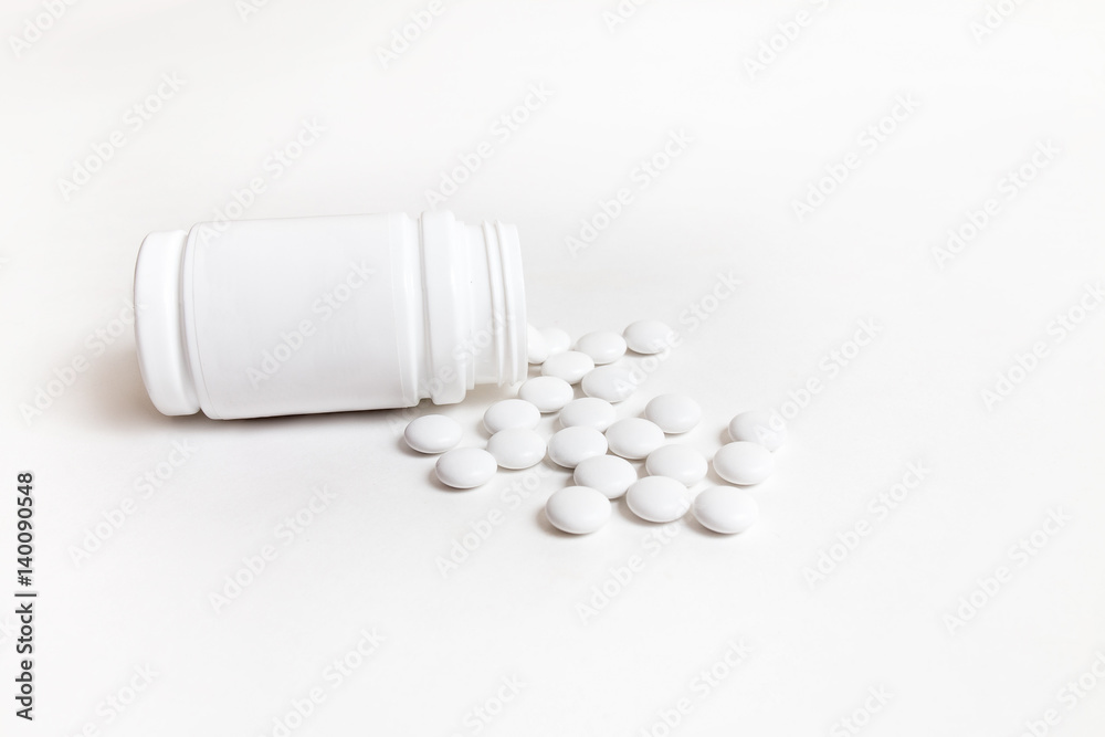 Vial with scattered medication tablets on white Vial with scattered medication tablets on white