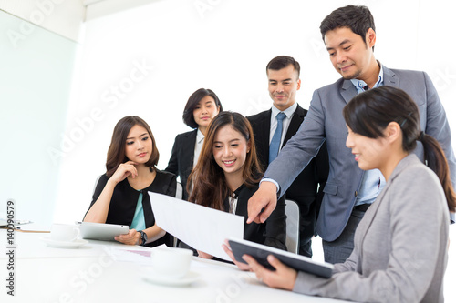Smiling businessman and his colleague looking at document in meeting
