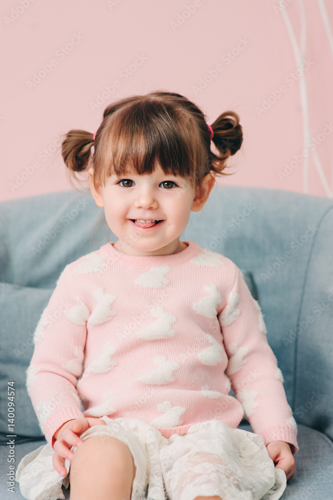 Fototapeta premium vertical close up indoor portrait of cute happy baby girl in pink sweater