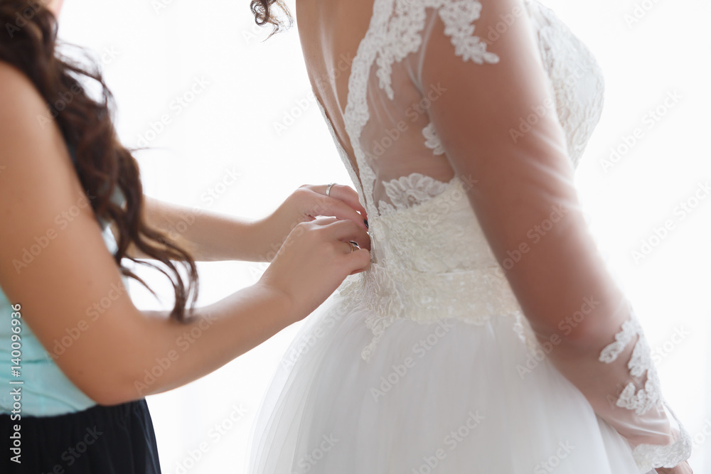 Wedding. Bridesmaid dresses bride for the wedding day. Bridesmaid helps bride with a wedding dress before the ceremony. Best wedding morning. Wedding concept