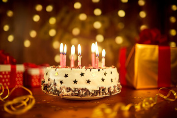 Happy birthday cake with candles on the background of garlands and letters.