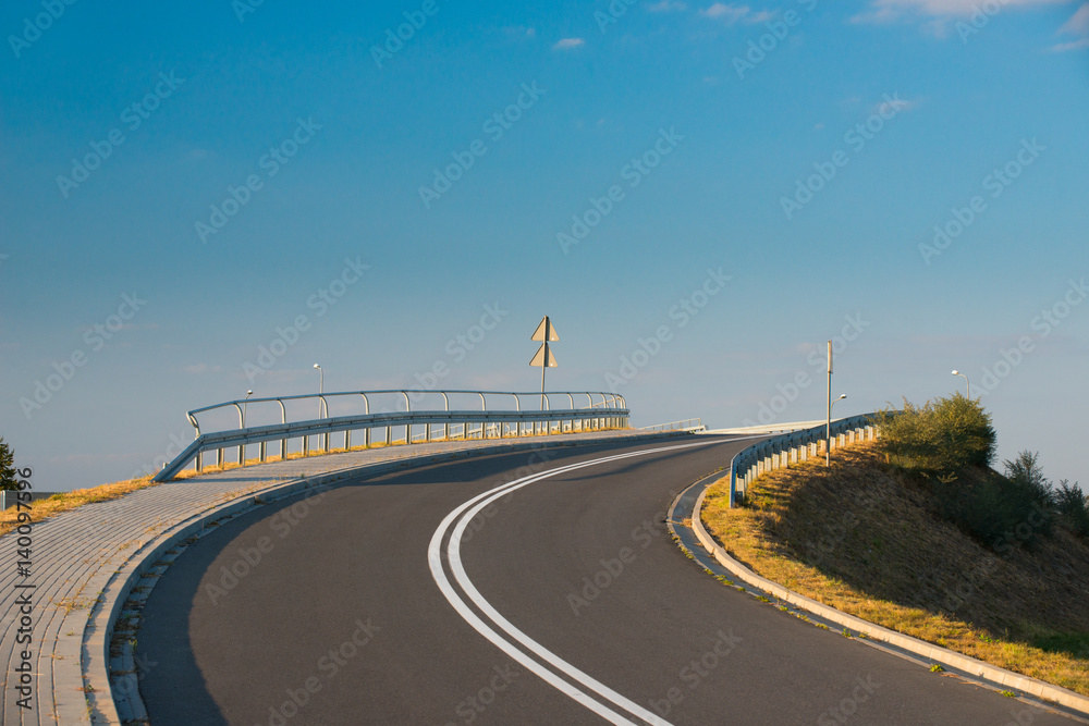 Fototapeta premium Wiadukt z asfaltową drogą przechodzący nad autostradą, łuk drogi