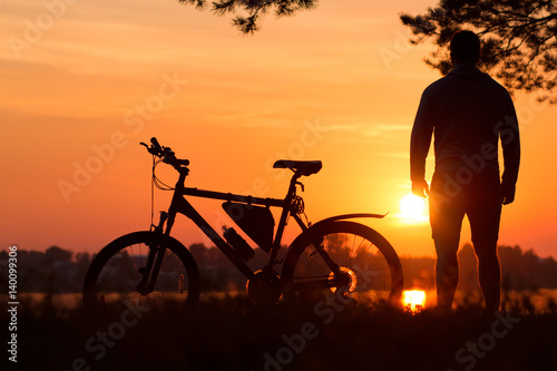 Cyclist at sunset .Bike at sunset near the lake under a pine tree