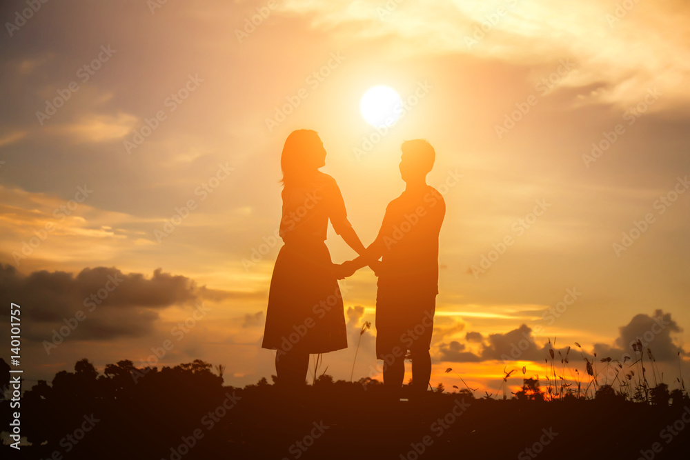 a silhouette of a man and woman holding hands with each other, walking together.