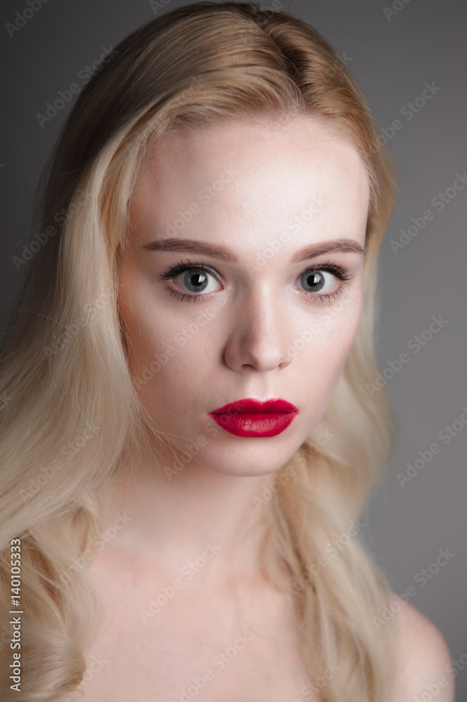 Beauty model girl with perfect make-up red lips and blue eyes looking at camera. Portrait of attractive young woman with blond hair. Beautiful female face with clear fresh skin. Fashion close up shot. Beauty model girl with perfect make-up red lips and blue eyes looking at camera. Portrait of attractive young woman with blond hair. Beautiful female face with clear fresh skin. Fashion close up shot.
