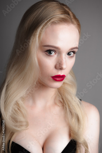 Beauty model girl with perfect make-up red lips and blue eyes looking at camera, wearing magenta bra. Portrait of attractive sexy young woman with blond hair. 