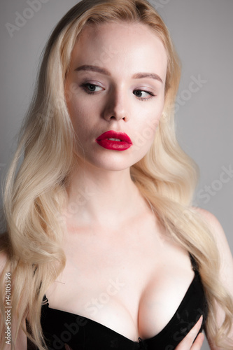 Beauty model girl with perfect make-up red lips and blue eyes looking at camera, wearing magenta bra. Portrait of attractive sexy young woman with blond hair. 