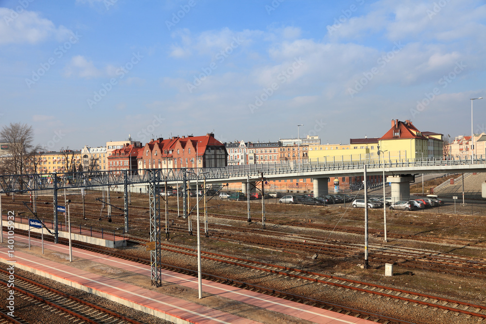 Szyny kolejowe, perony na dworcu w Opolu, zabytkowe kamienice.