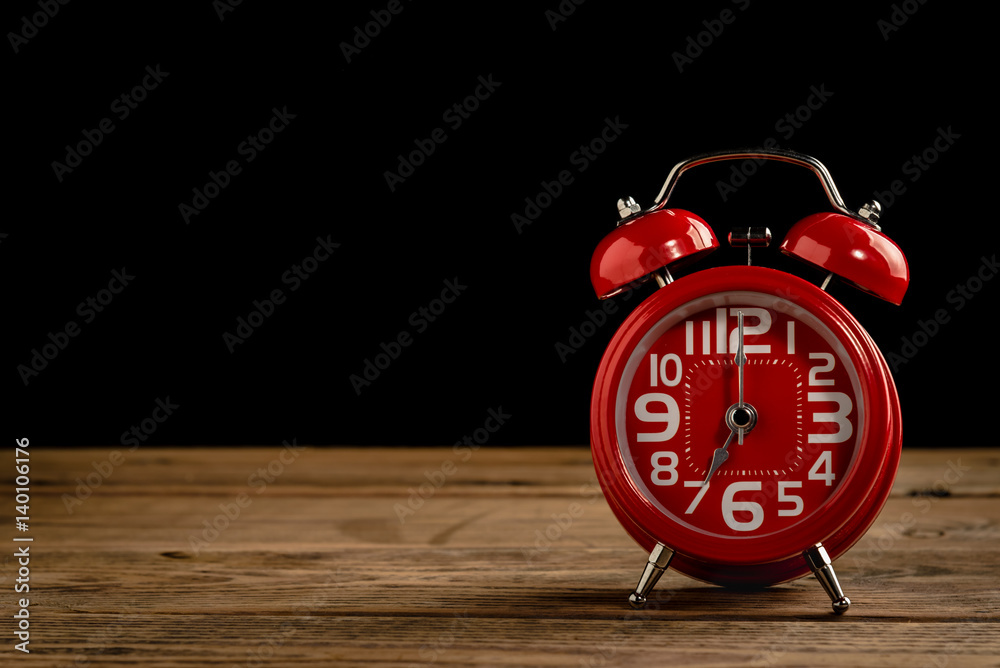 Red alarm clock on wood table with black background. Red alarm clock on wood table with black background.