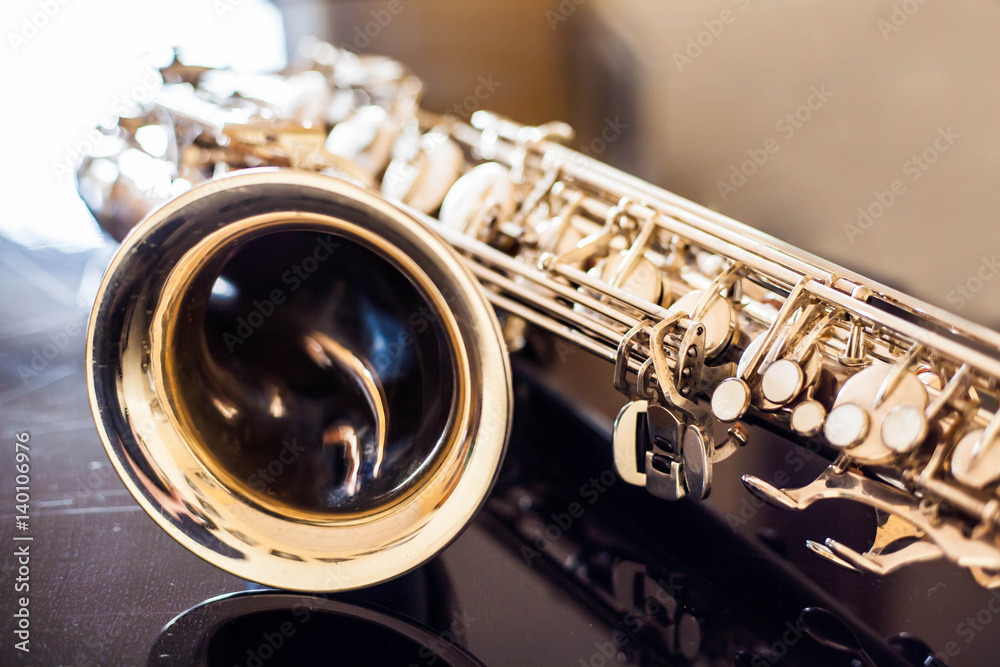 Fototapeta premium Saxophone tenor. Woodwind Classical Instrument. Jazz, blues, classics. Music. Saxophone on a black background. Black mirror surface. Music styles