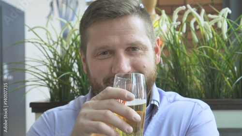Smiling businessman looking at camera, drink beer, pub, close steadycam portrait