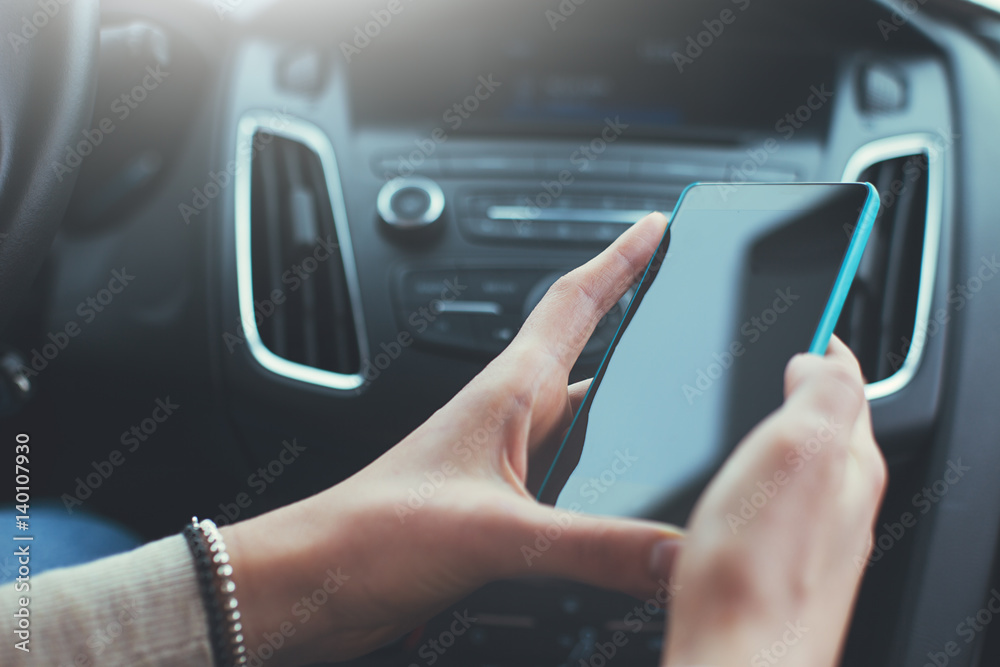 Close-up of woman's hands holding smartphone in the car interior Close-up of woman's hands holding smartphone in the car interior