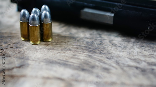 Bullets and a firearm on the wood. Bullets are a projectile expelled from the barrel of a firearm.