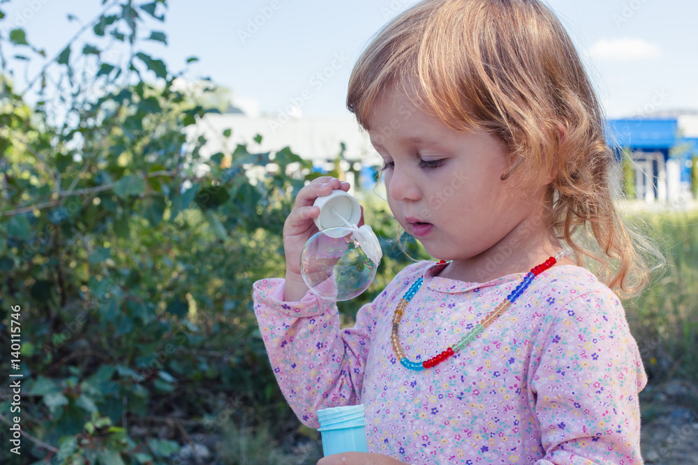 A curly little girl blowing soap bubbles. A curly little girl blowing soap bubbles.